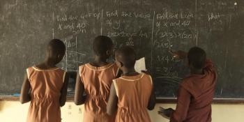 Schoolgirls write on chalkboard