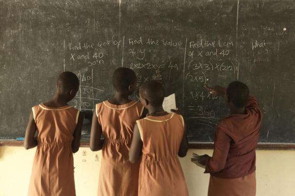 Schoolgirls write on chalkboard